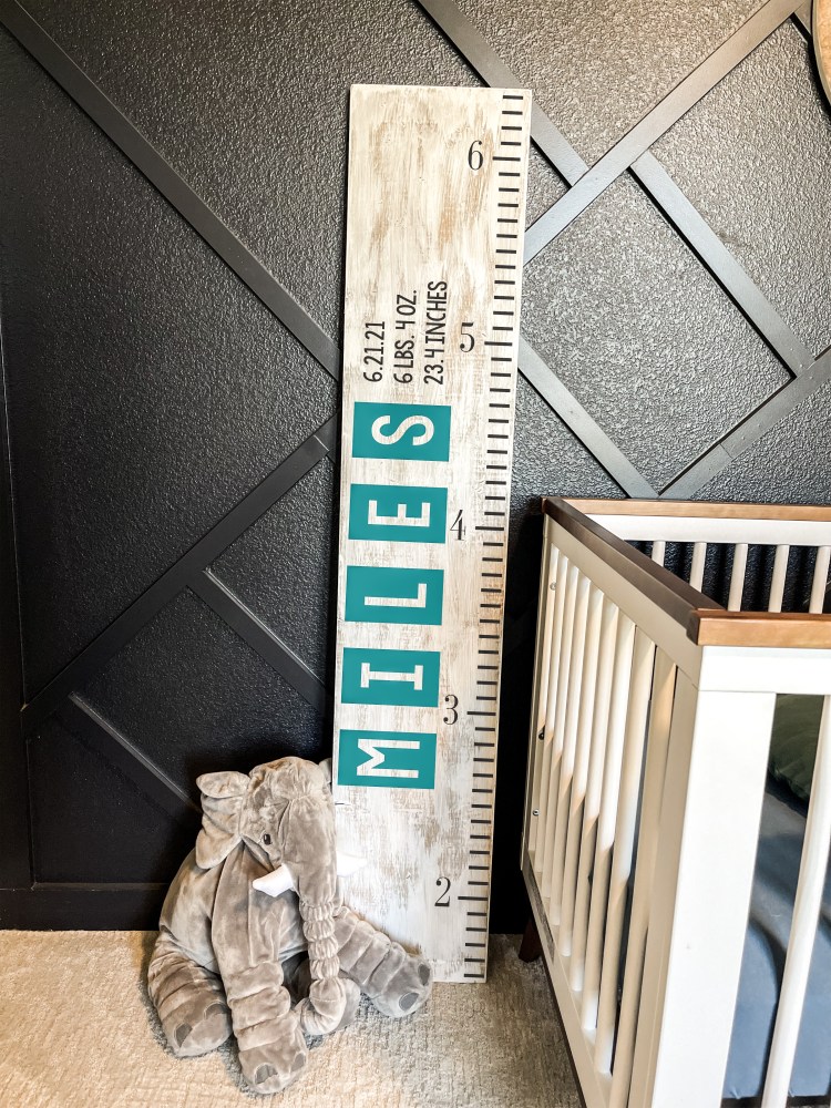 Nursery with elephant toy, crib, and height chart labeled 'MILES' against a black wall.