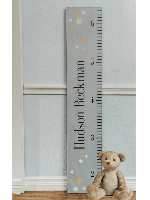 Wooden growth chart with stars and a teddy bear next to it.