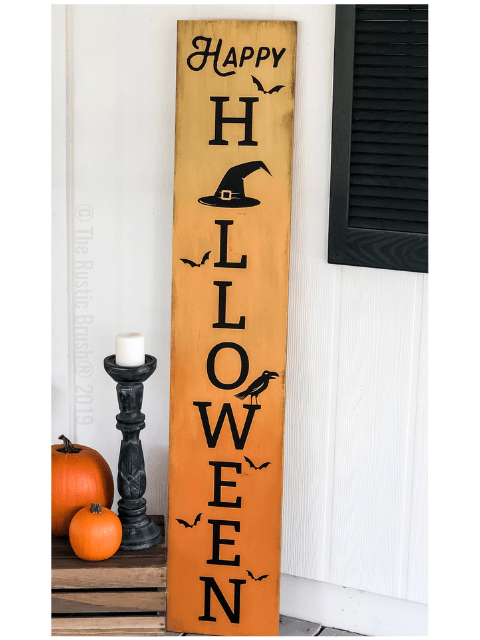 Tall sign with 'Happy Halloween' and witch's hat, bats, pumpkins, and candle decor.