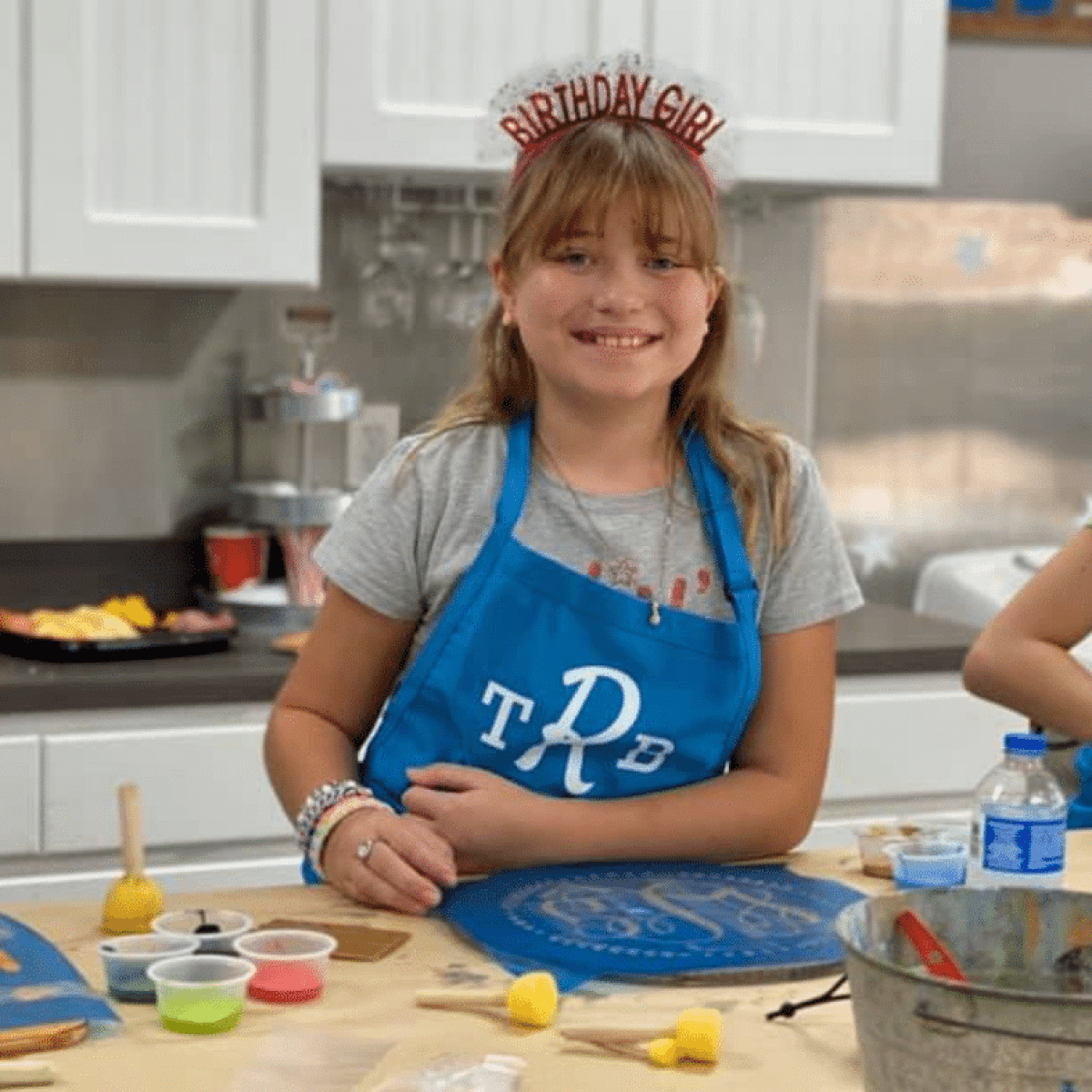 a little girl standing in a kitchen preparing food