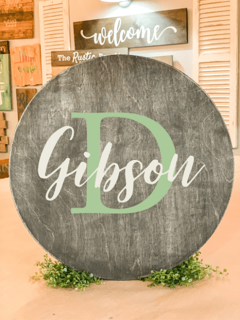 Wooden sign with 'Gibson' and large 'D', surrounded by green leaves.