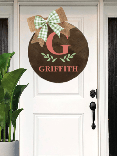White door with round decor reading 'Griffith' and a bow on top, plant on left.