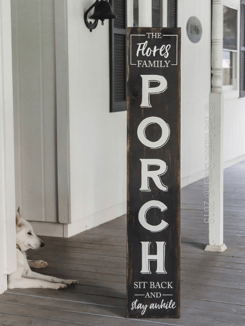 Tall porch sign with 'PORCH' text and lounging dog on a wooden porch.