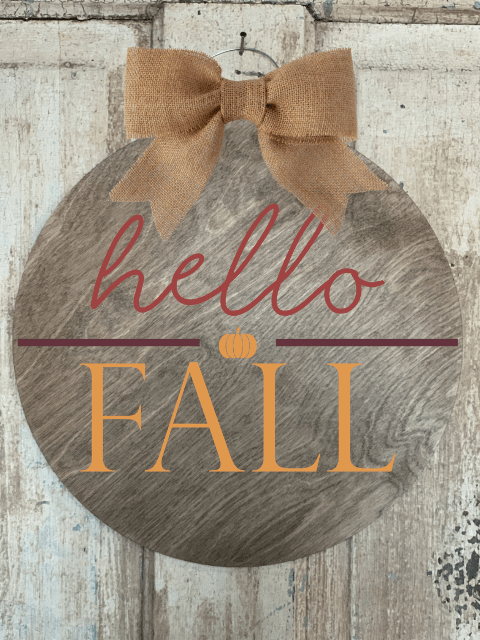 Wooden sign with 'hello FALL' text and burlap bow on a rustic background.