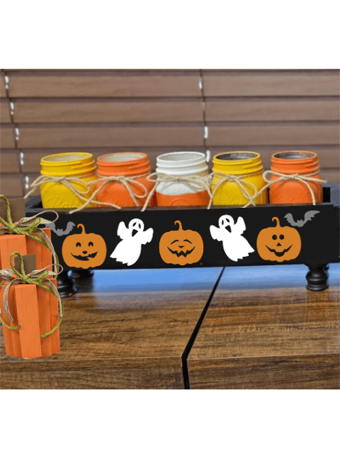 Halloween-themed jars and pumpkins with ghost and bat motifs on a wooden table.