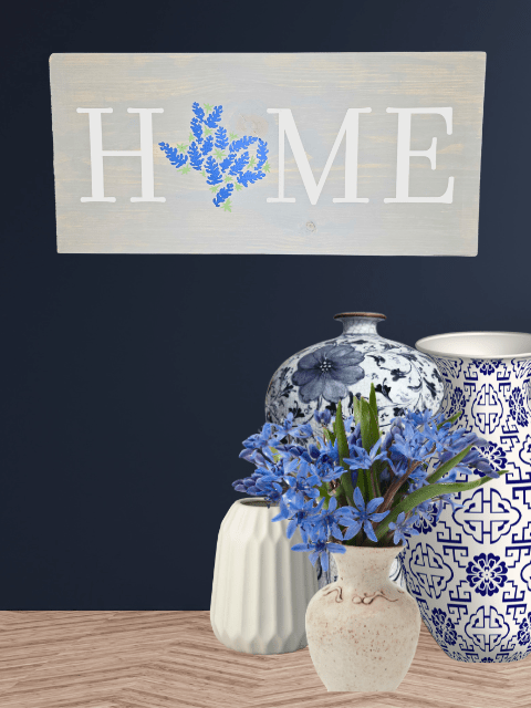 Sign with 'HOME' and blue flowers above vases with blue floral patterns and blue flowers below.