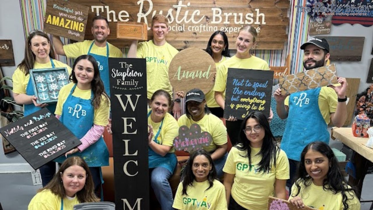Group of people holding crafty signs at The Rustic Brush workshop.