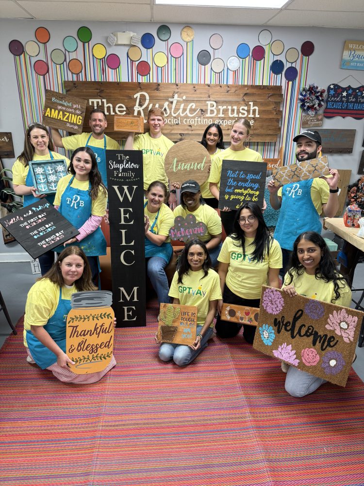 Group of people in yellow shirts holding handmade signs in a craft workshop.