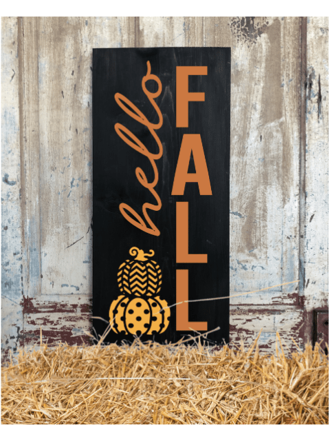 Sign with 'hello FALL' and pumpkin art on hay bales against rustic wall.