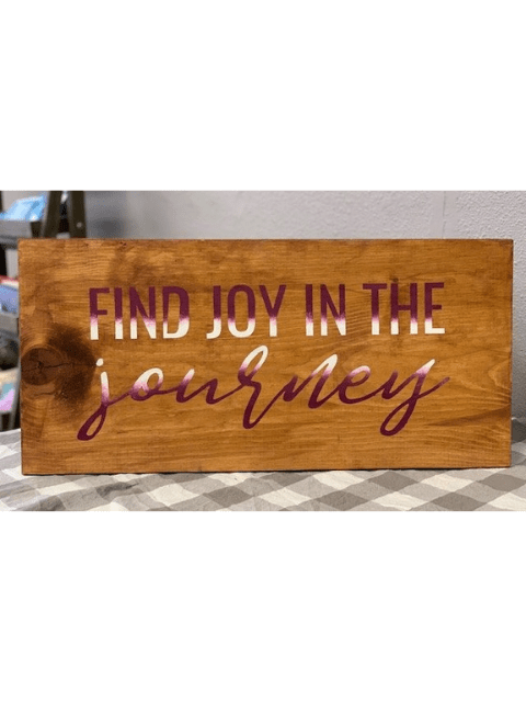 Wooden sign reading 'Find joy in the journey' in purple letters.