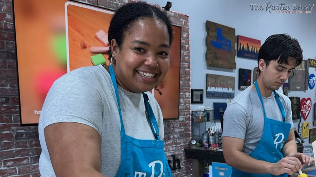 Two people in blue aprons crafting in an art studio.