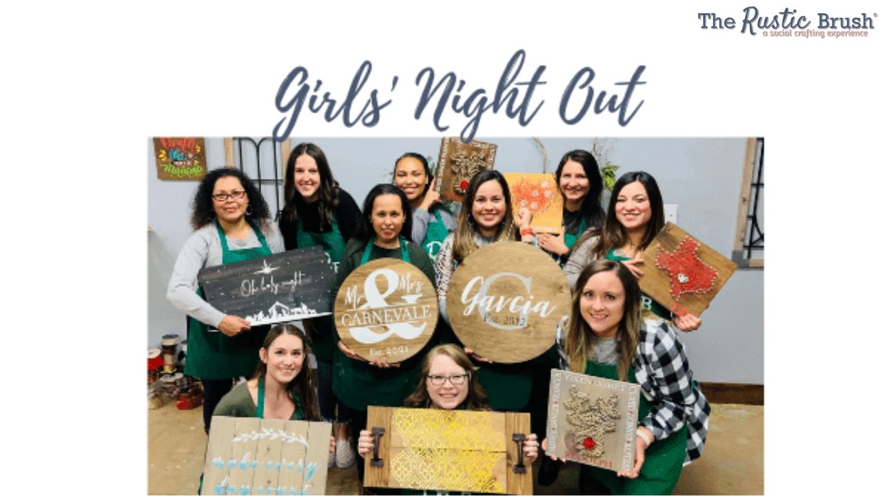 Group of women in aprons holding custom wooden signs at a crafting event titled 'Girls' Night Out'.