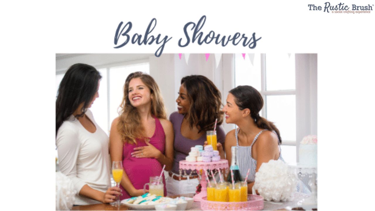 Four women smiling at a baby shower with cupcakes and drinks on a table.