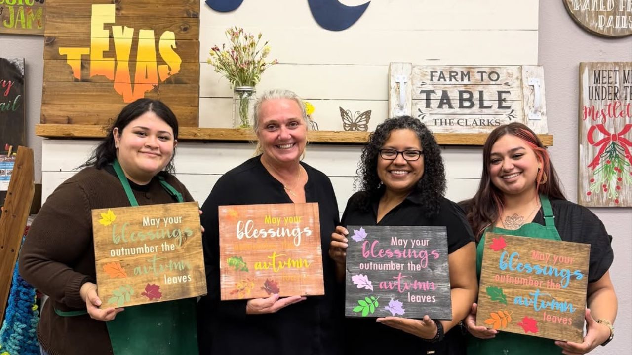 Four people holding fall signs at BYOB craft workshop.
