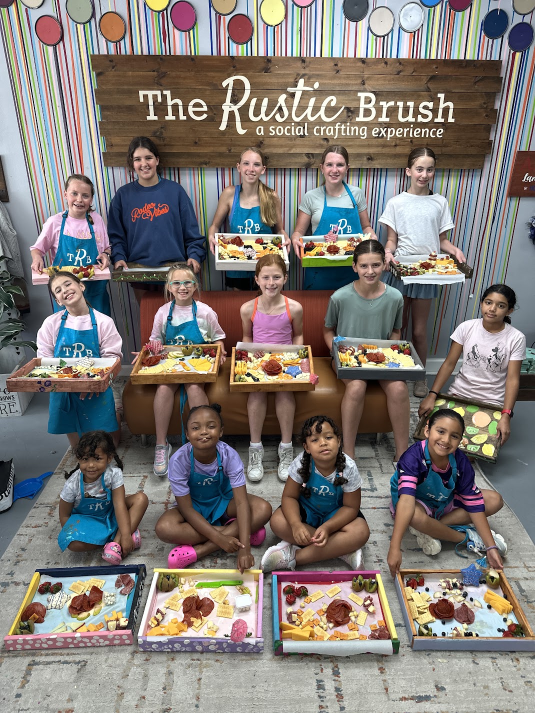 Group of children and teens holding craft trays at The Rustic Brush studio.