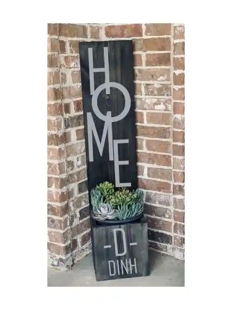 Handcrafted wooden home sign with decorative planter.