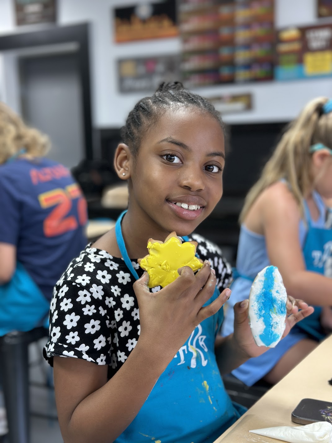 Child showing a painted craft project at an art workshop.