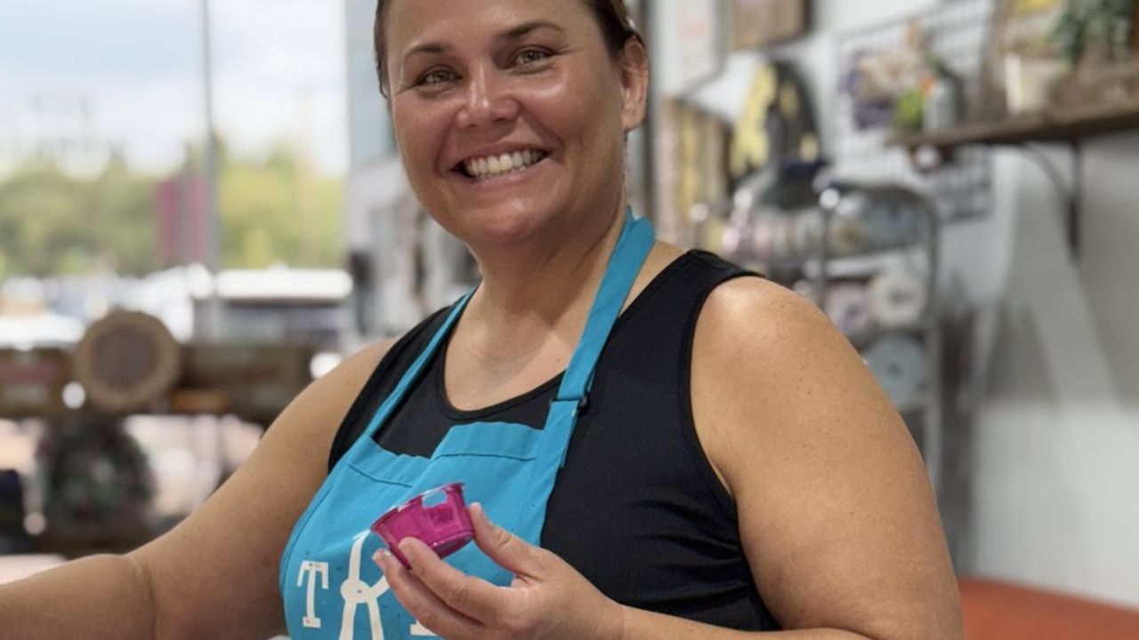 Woman painting a wooden craft project while wearing an apron at The Rustic Brush DIY studio.