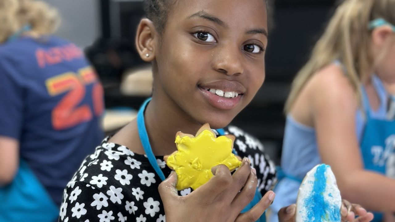 Girl holding painted craft pieces during a children’s art camp activity