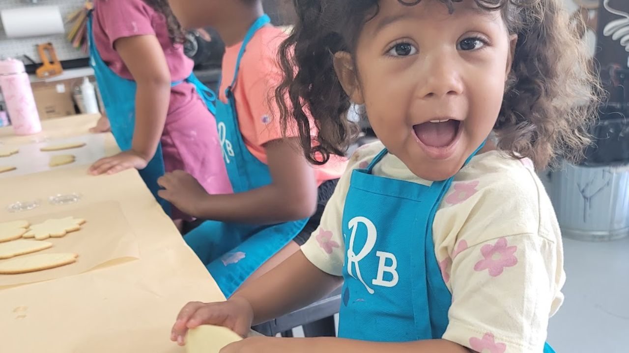 Young child decorating cookie shapes during a children’s art camp activity 