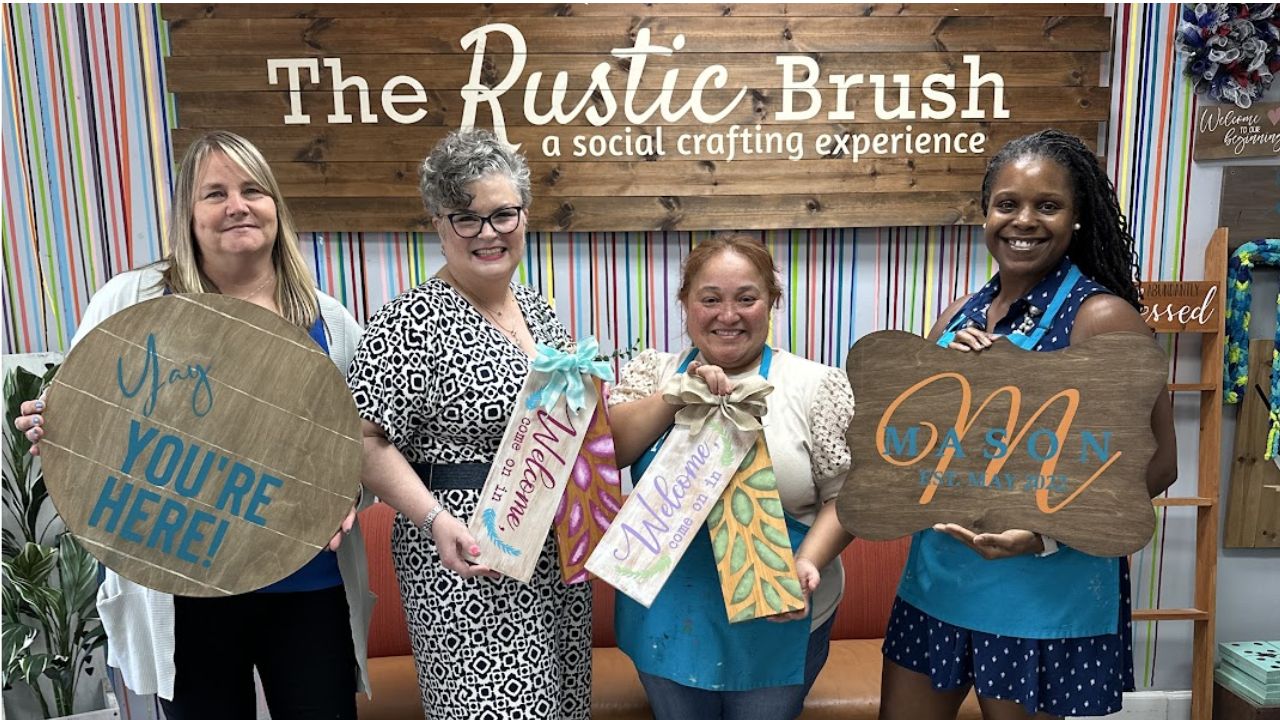 Group of participants smiling and showcasing their personalized DIY wooden signs