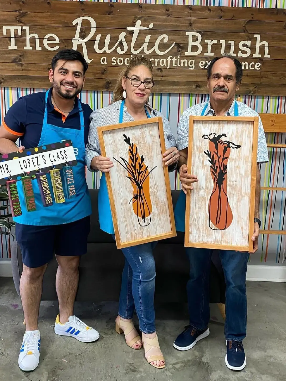 Adults holding framed DIY artwork at The Rustic Brush