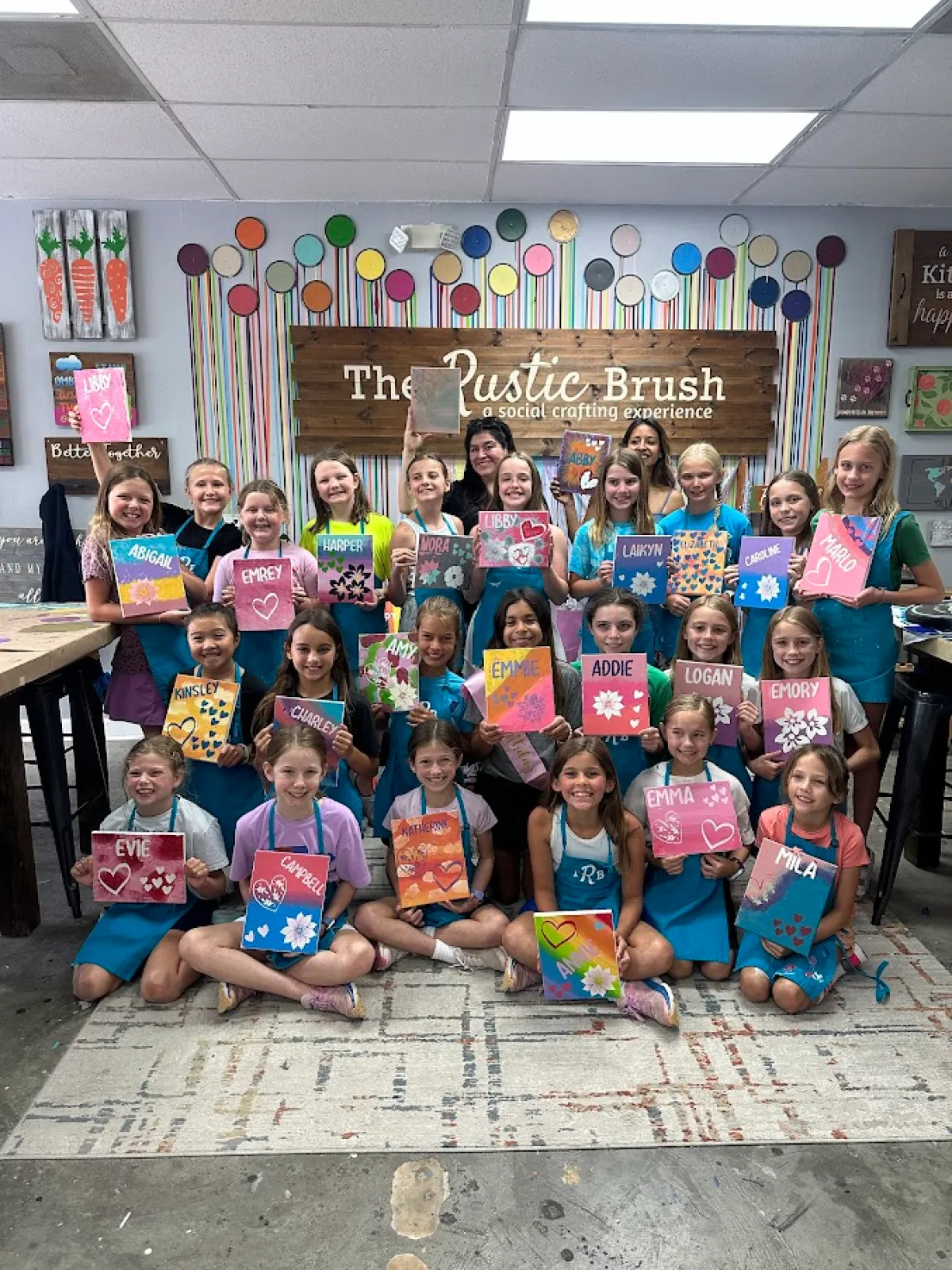 Kids art party group holding painted canvases at The Rustic Brush