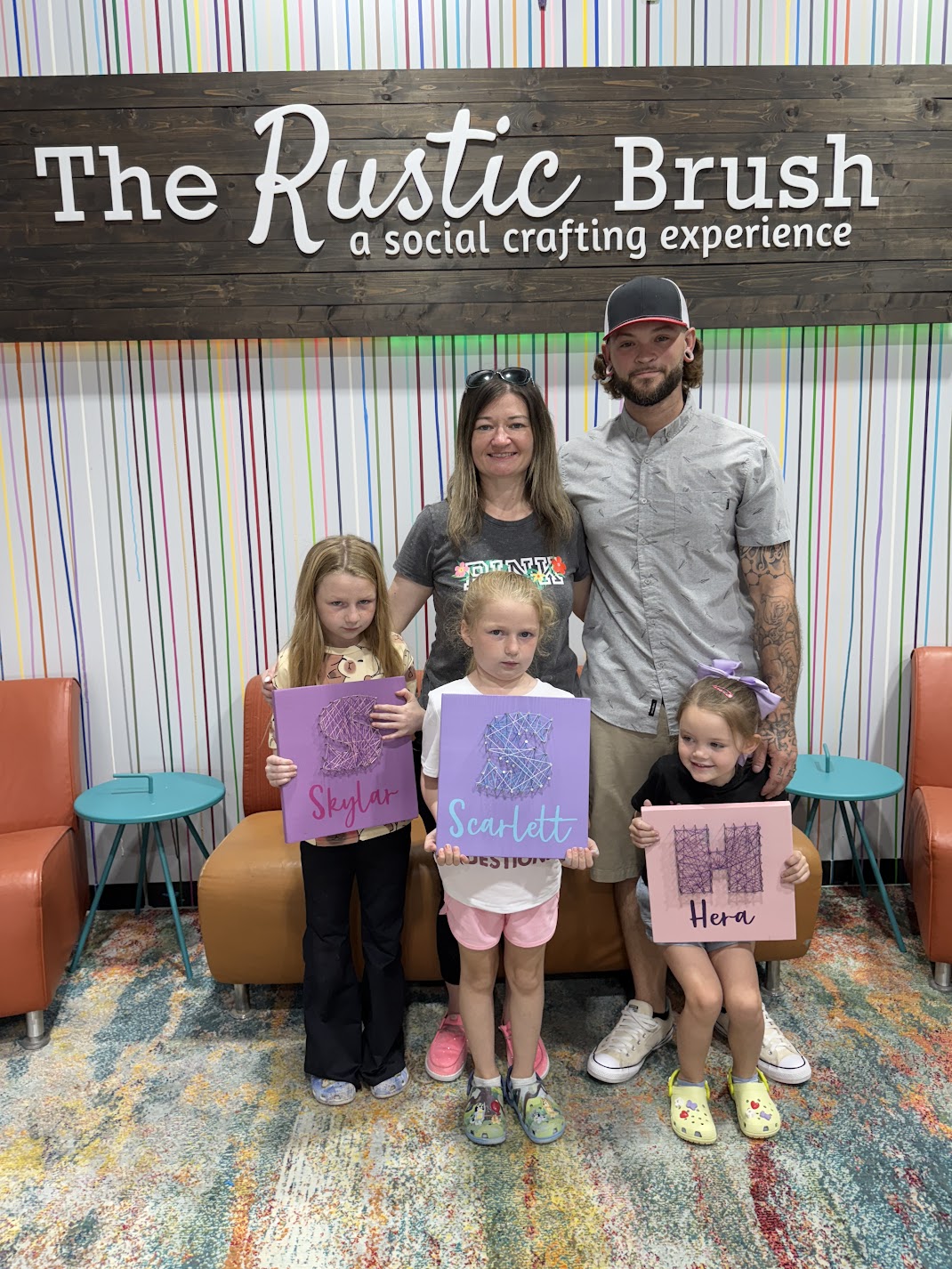 Parents and kids posing with custom string art signs at DIY workshop