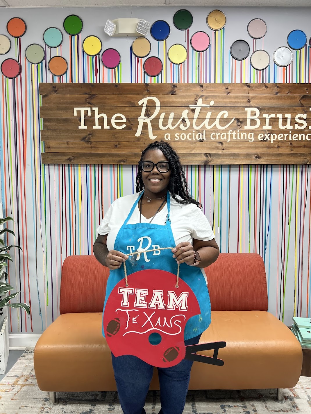 Woman holding custom Team Texas craft sign at The Rustic Brush studio