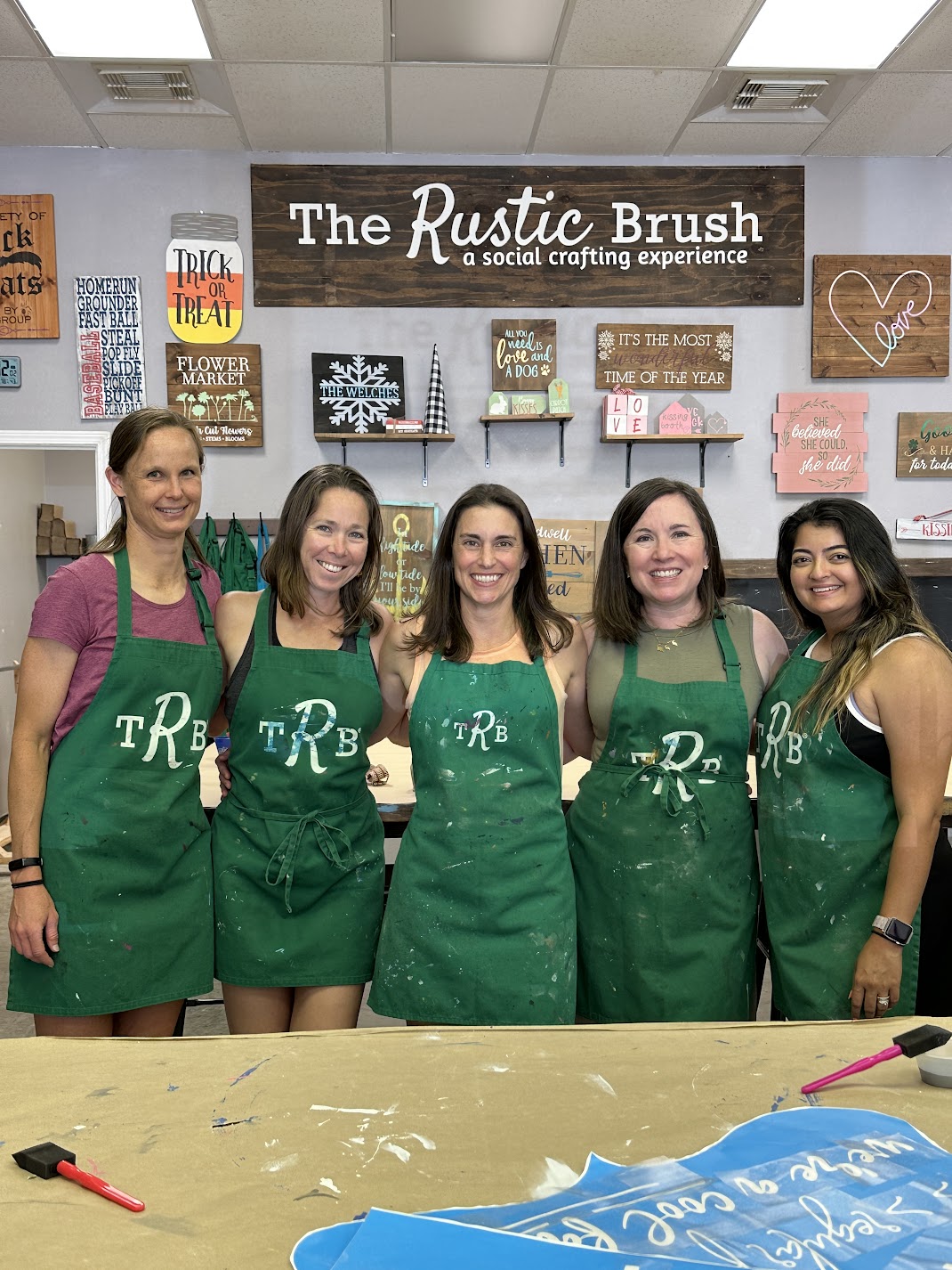 Women in aprons smiling during group craft workshop session