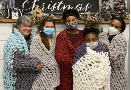 Group displaying handmade chunky knit blanket creations.