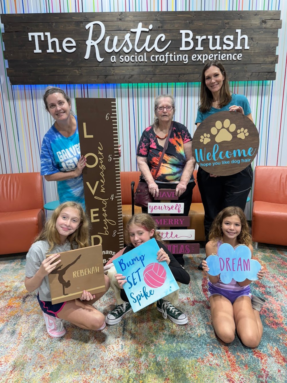 Multi-generational group proudly displaying personalized wood sign projects at The Rustic Brush.