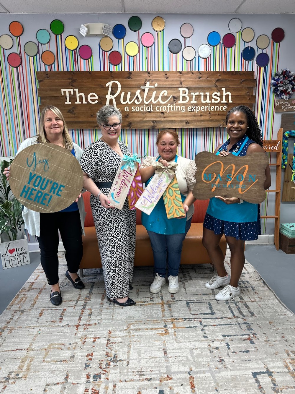 Participants proudly displaying their completed custom wood sign creations at The Rustic Brush