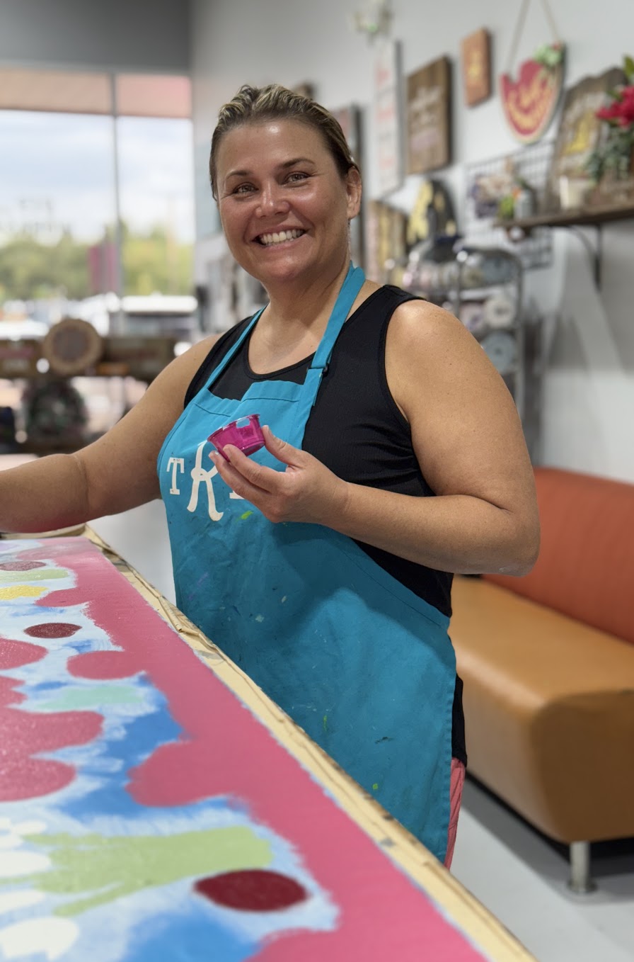 Woman painting a colorful custom wood sign during a DIY crafting workshop.