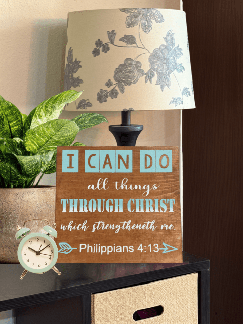 Lamp and clock on table with Philippians 4:13 quote sign.