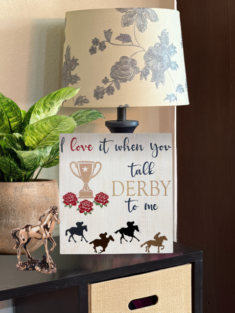 Lampshade with floral design next to Derby-themed sign and plant.