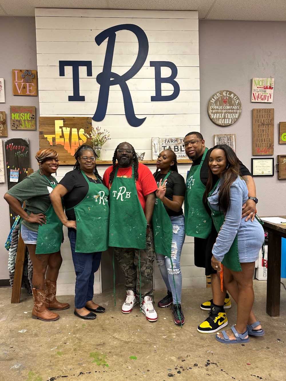 Group of friends wearing aprons posing in a craft workshop.